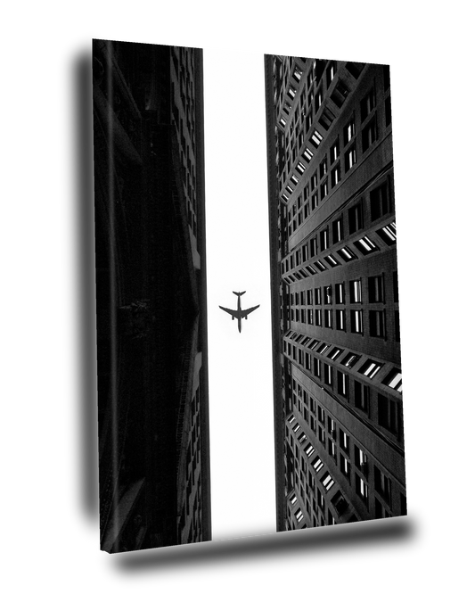 Cuadro Decorativo Avión volando sobre dos edificios Blanco y Negro